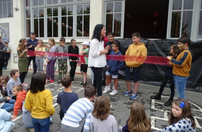 Les enfants de l'ALAE de Cardeilhac, au signal de la directrice Martine Jacomet, coupent le ruban inaugural de la fresque de mosaïque à laquelle ils ont participé.