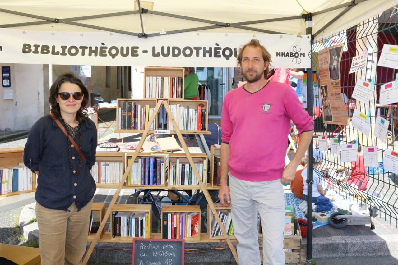 Laure et Raphaël, de l'association N'Kabom, sur le stand de la bibliothèque consacrée à l'Afrique, pendant le marché de l'Isle-en-Dodon.