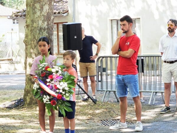 Les enfants déposent une gerbe de fleurs au monument aux Morts à Saint-Laurent, dans le cadre de la fête locale. (au centre Enzo Dulerm, président du Comité)
